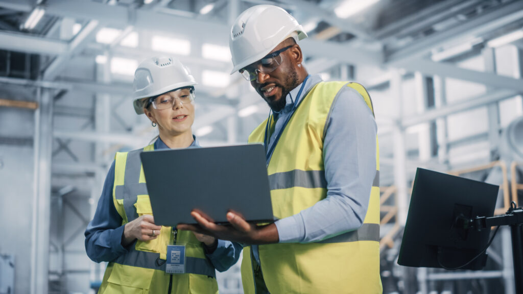 Two construction workers looking at a laptop on a construction site